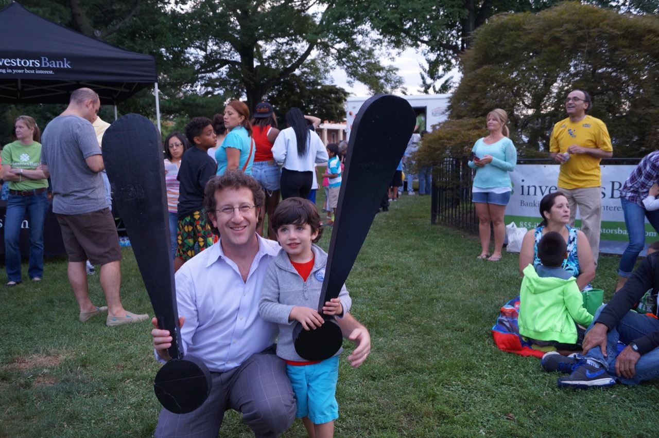 A man and little boy hold the Share the Fun exclamation points.